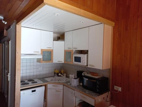 une cuisine avec des armoires blanches, un évier et un micro-ondes dans l'établissement Duplex 4 pièces, balcon Sud/Ouest, 100m des pistes - FR-1-449-94, à Tignes