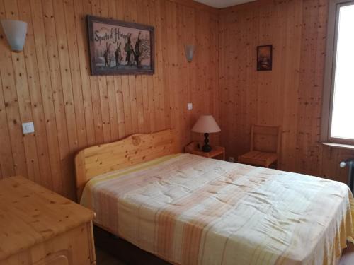 une chambre avec un lit dans une pièce aux murs en bois dans l'établissement T2 avec balcon sud/ouest à 500 m des pistes - FR-1-449-137, à Tignes