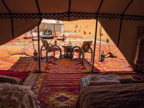 uma tenda com uma mesa e cadeiras em frente a uma praia em Sahara luxury camp & activities em Merzouga