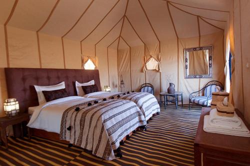 um quarto com uma cama grande numa tenda em Sahara luxury camp & activities em Merzouga