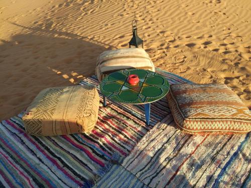 um cobertor sobre a areia com uma mesa sobre ele em Sahara luxury camp & activities em Merzouga