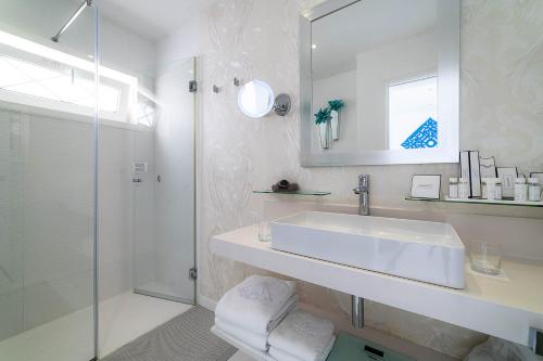 a white bathroom with a sink and a shower at Lani's Suites de Luxe - Adults Only in Puerto del Carmen