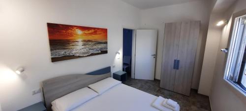 1 dormitorio con 1 cama y una pintura en la pared en Casa Vacanza GOCCIA D'ORO con possibilità di Monolocale oppure Bilocale, en Porto Cesareo