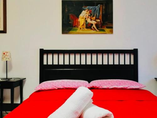 a red bed with two pink pillows and a painting at Casa Mirandola in Rome