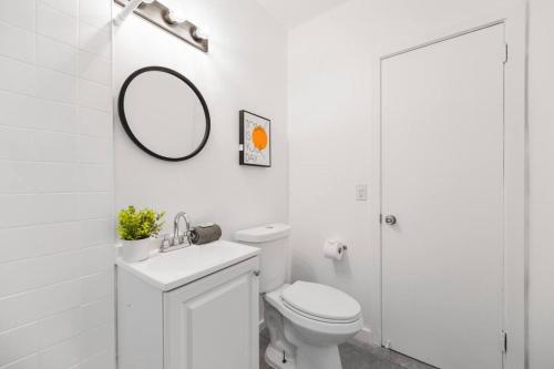 bagno bianco con servizi igienici e specchio di Awesome Studio 15 min from The Beach a Miami