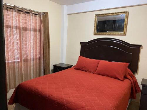 1 dormitorio con 1 cama con edredón rojo y ventana en Apartamento #2 Portal de Occidente, en Quetzaltenango