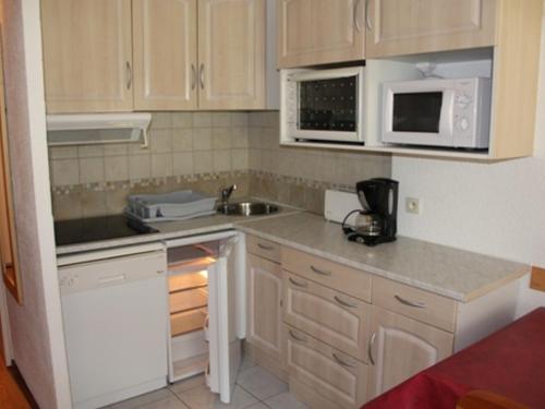 La cuisine est équipée de placards blancs, d'un évier et d'un four micro-ondes. dans l'établissement Studio cosy de 25m² au pied des pistes avec balcon - FR-1-449-8, à Tignes