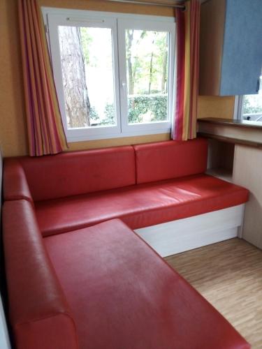 un sofá rojo en una habitación con ventana en Mobil-home 6 personnes 3 chambres, en La Boissière-de-Montaigu