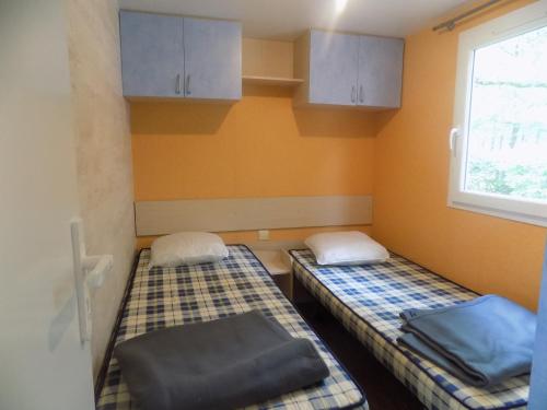 2 camas en una habitación con ventana y armarios en Mobil-home 6 personnes 3 chambres, en La Boissière-de-Montaigu