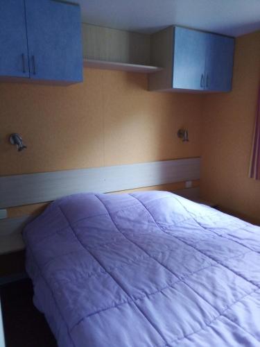 Cama grande en habitación con armarios azules en Mobil-home 6 personnes 3 chambres, en La Boissière-de-Montaigu