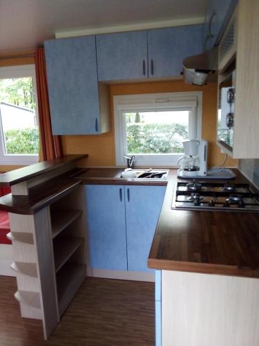 una pequeña cocina con armarios azules y fregadero en Mobil-home 6 personnes 3 chambres, en La Boissière-de-Montaigu