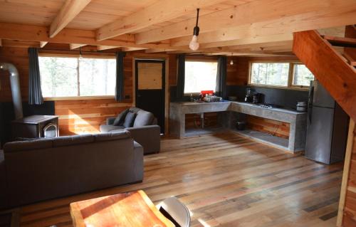 ein Wohnzimmer mit einem Sofa und einer Küche in der Unterkunft Acogedora Cabaña del Bosque - Parque La Pirámide 