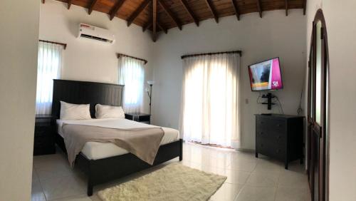 een slaapkamer met een bed, een tv en ramen bij Villas for Vacation 32-18-6 in Sosúa