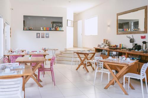 ein Restaurant mit Holztischen, Stühlen und einem Spiegel in der Unterkunft Pousada CafeMar Búzios in Búzios