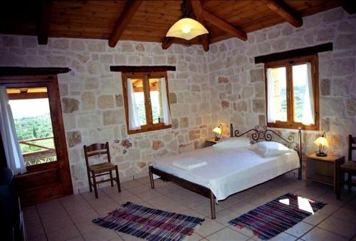 Villa Belvedere - Sea view apts near Banana beach في فاسيليكوس: غرفة نوم بسرير وكرسي في غرفة