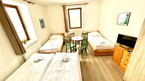 a small room with two beds and a table at Penzion Dolní Morava in Dolní Morava