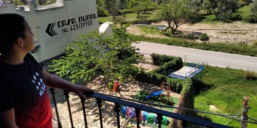 a man standing on a balcony looking at a playground at La Casa del Carrebaix in Orba
