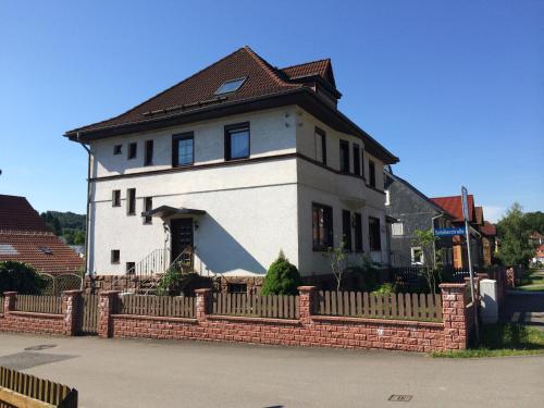 une grande maison blanche avec une clôture en briques dans l'établissement FeWo Rennsteigschloß, à Benshausen
