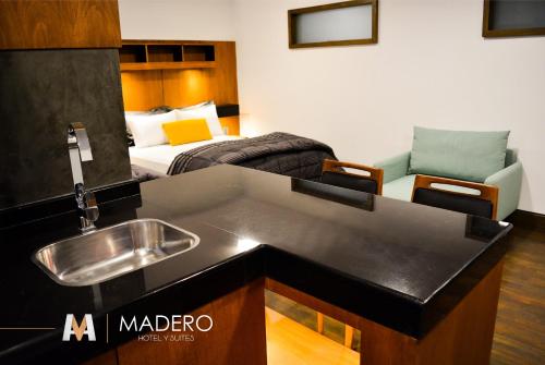 a kitchen with a sink and a living room with a bed at Madero Hotel & Suites in La Paz