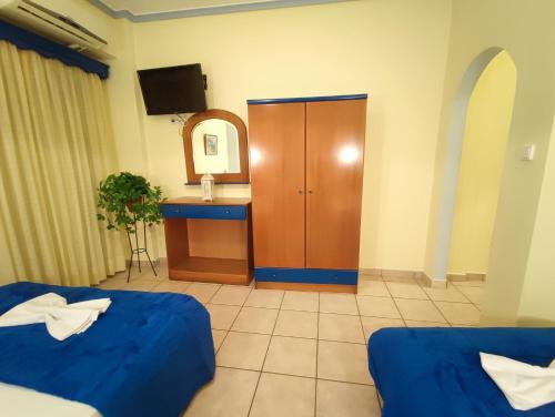 a room with two beds and a cabinet and a mirror at Studios Dafni in Paralia Katerinis