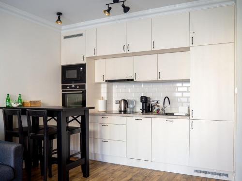 a kitchen with white cabinets and a table at Brick House - Apartament Zośka in Wrocław