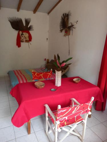 une table avec un tissu de table rouge et deux chaises dans l'établissement Chez cloclo, au Gosier