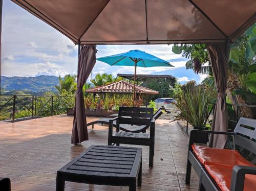 a patio with a table and a blue umbrella at Glamping Montecarlo Lodge Cubo de Madera-Guatapé in Guatapé