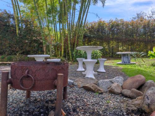 a garden with three picnic tables and a stone grill at Glamping Montecarlo Lodge Cubo de Madera-Guatapé in Guatapé