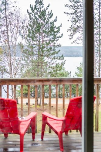two red chairs on a porch with a view of the water at Muskoka Waterfront Retreat in Dwight