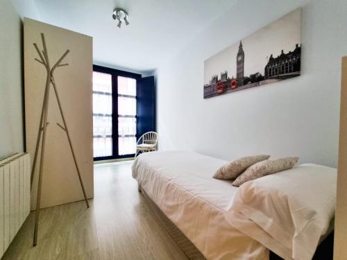 a white bedroom with a bed and a large window at BarloventoCudillero in Cudillero