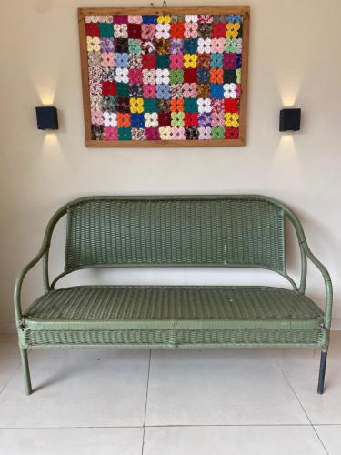 a green bench in a room with a quilt on the wall at Casa Canto do Bambu in Delfinópolis