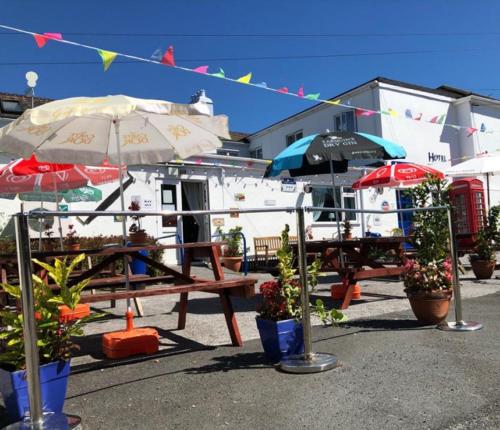 a picnic table with umbrellas and plants in front of a building at The Sportsmans Inn Limited in Ivybridge