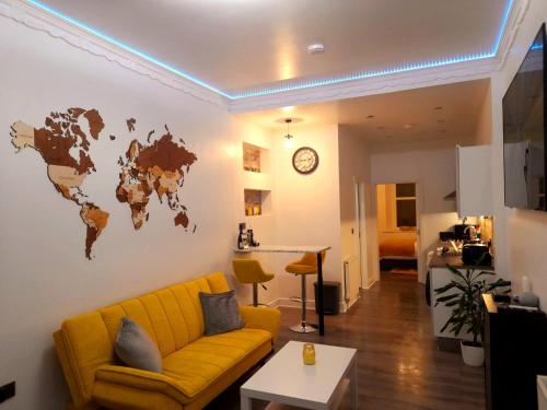 a living room with a yellow couch and a world map on the wall at Modern flat near city centre. in Edinburgh