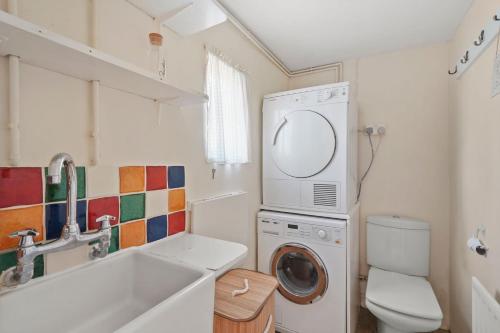 a small bathroom with a washing machine and a sink at 6 Bed Countryside Mansion With Tennis Court & Swimming Pool with Parking in East Horsley