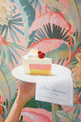 a person holding a piece of cake on a plate at Hamilton Princess & Beach Club A Fairmont Managed Hotel in Hamilton