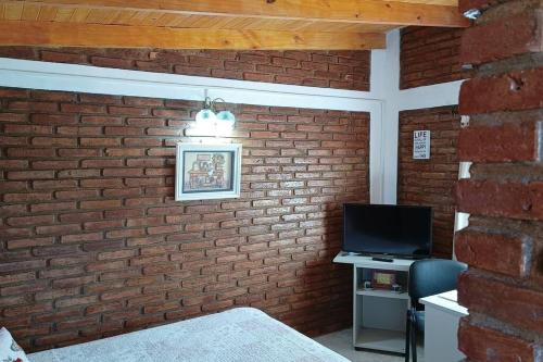 Habitación con pared de ladrillo y TV. en estudio CL, monoambiente confortable en El Calafate