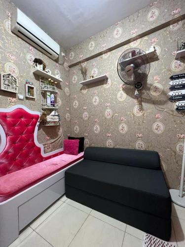 Cette chambre dispose d'un canapé rose et d'un ventilateur. dans l'établissement Homestay Jakarta, à Pondokcabe Hilir