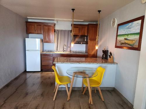 a small kitchen with a table and two yellow chairs at Maya Beach Hotel in Maya Beach