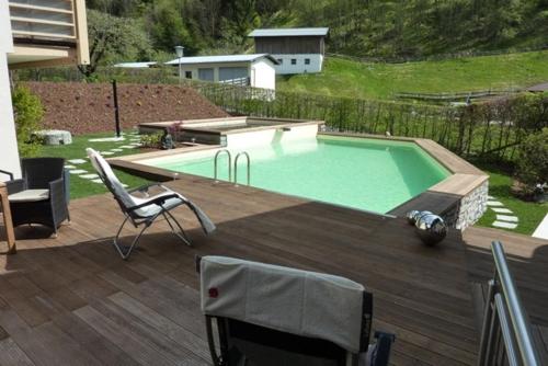 a swimming pool on a deck with a chair and a table at Pension Mühle in Zell am See