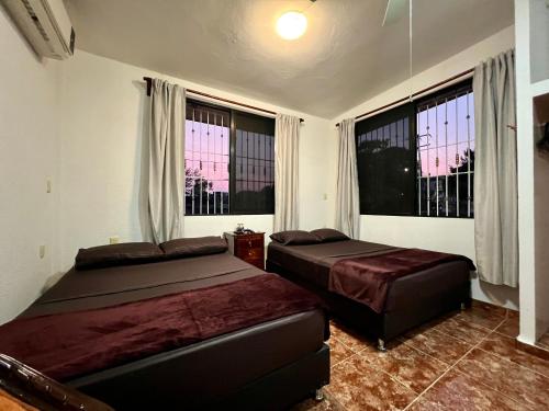 1 dormitorio con 2 camas y 2 ventanas en Family queen size, en Minatitlán