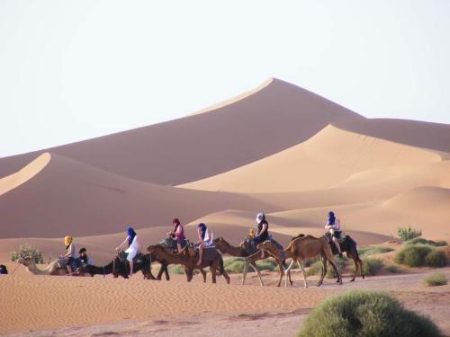 a group of people riding horses in the desert at Camp Golden Desert Morocco in Mhamid