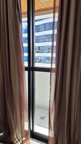 una ventana con cortinas y vistas a un edificio en Ótimo Ap na Pajuçara - Maceió, en Maceió