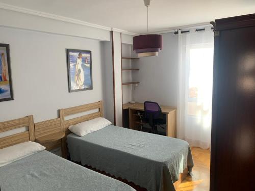 a room with two beds and a desk and a window at Apartamento Santander in Santander