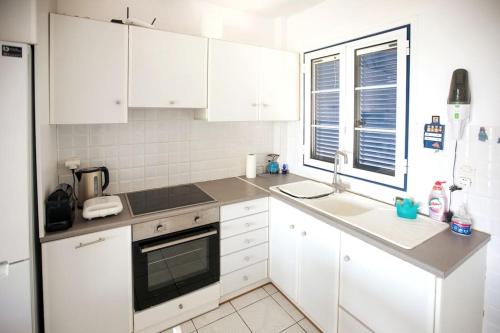 a kitchen with white cabinets and a sink and a window at Karantou in Tiros