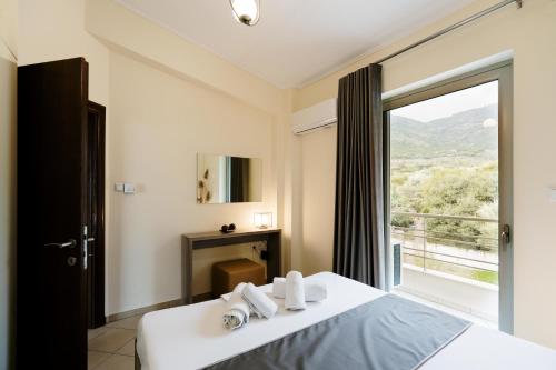 sypialnia z łóżkiem i dużym oknem w obiekcie Our House Luxury Suites w mieście Palaión Tsiflíkion