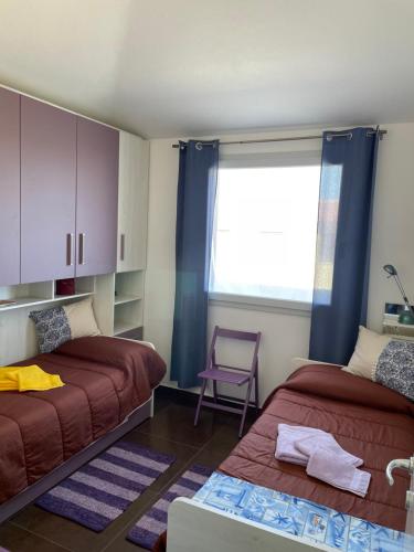 - une chambre avec deux lits, une fenêtre et une chaise dans l'établissement Blue Sardinia Tourism, à Budoni