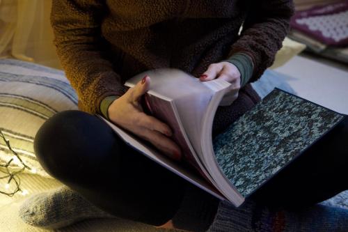a woman sitting on a couch reading a book at 3ART recreation in Tromsø