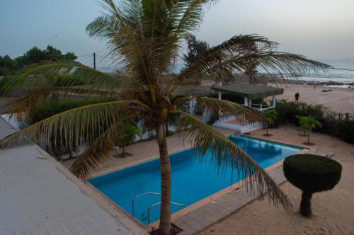 a palm tree next to a swimming pool next to the beach at Sur la Plage Yenne in Yenne-Todé