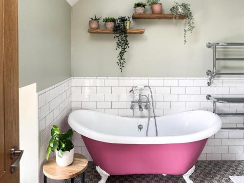 a pink bath tub in a bathroom with plants at The Cart House in Duns