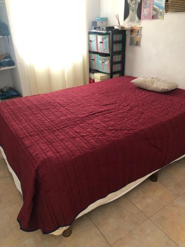 a bed in a room with a red comforter at Depto Duplex Cancún (Cuarto) in Cancún
